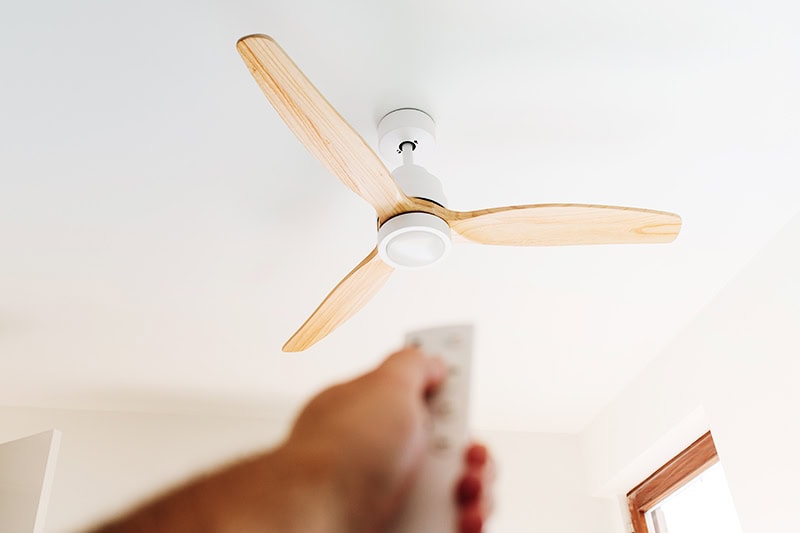 How to Choose the Right Ceiling Fan for Your Space. A person turning on a celling fan.